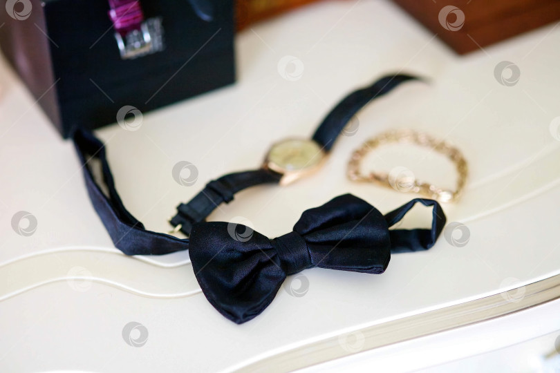 Скачать Мужской черный галстук-бабочка лежит на поверхности стола фотосток Ozero