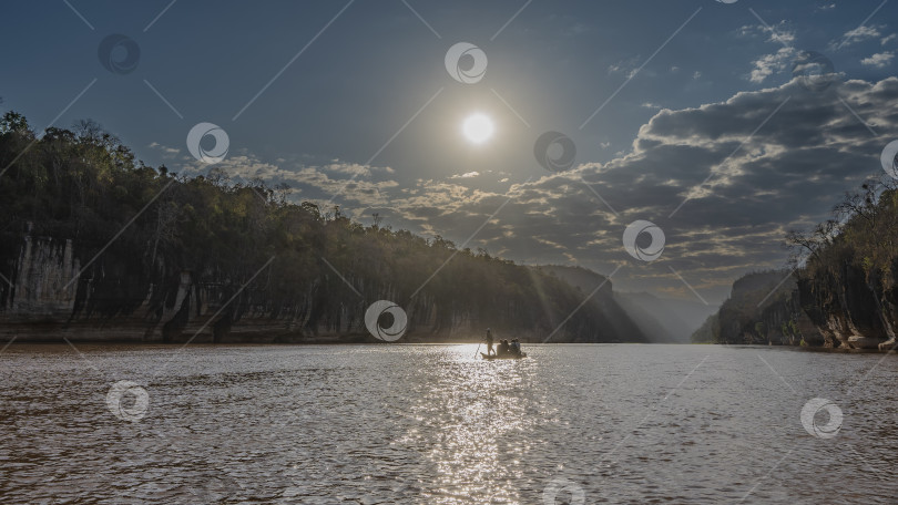 Скачать Каноэ с туристами плывет по спокойной красно-коричневой реке. фотосток Ozero