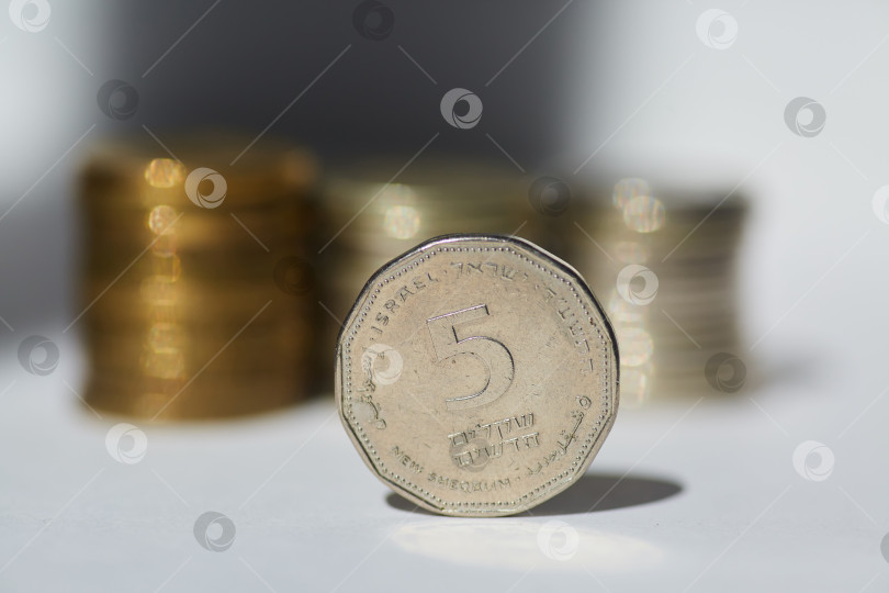 Скачать Монеты различных номиналов страны Израиль лежат на белой поверхности. Концепция экономики. фотосток Ozero