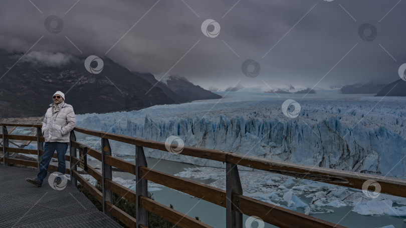 Скачать Мужчина в пуховике стоит на смотровой площадке ледника Перито Морено фотосток Ozero