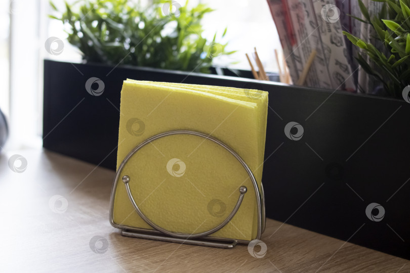 Скачать Желтые салфетки в металлической подставке на столе фотосток Ozero