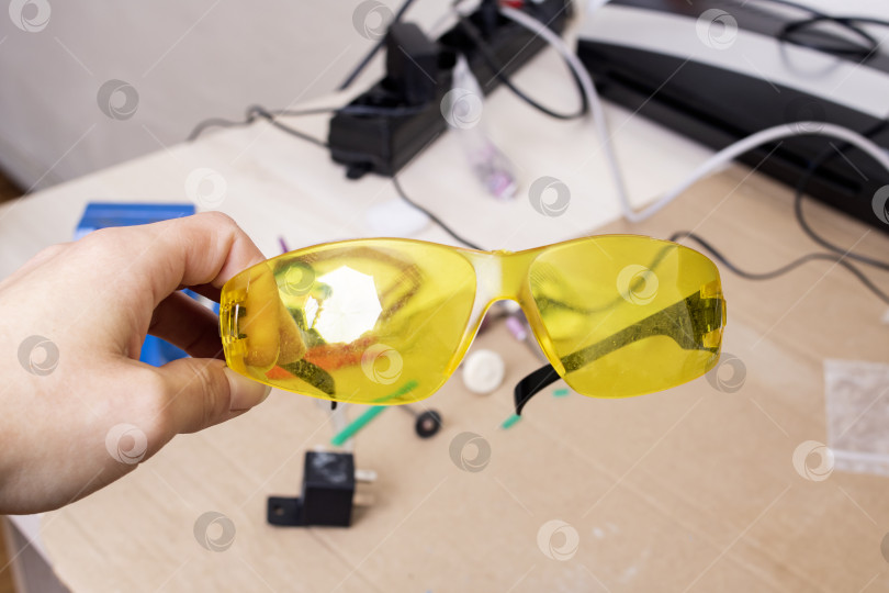 Скачать Желтые защитные очки в руке на рабочем столе фотосток Ozero