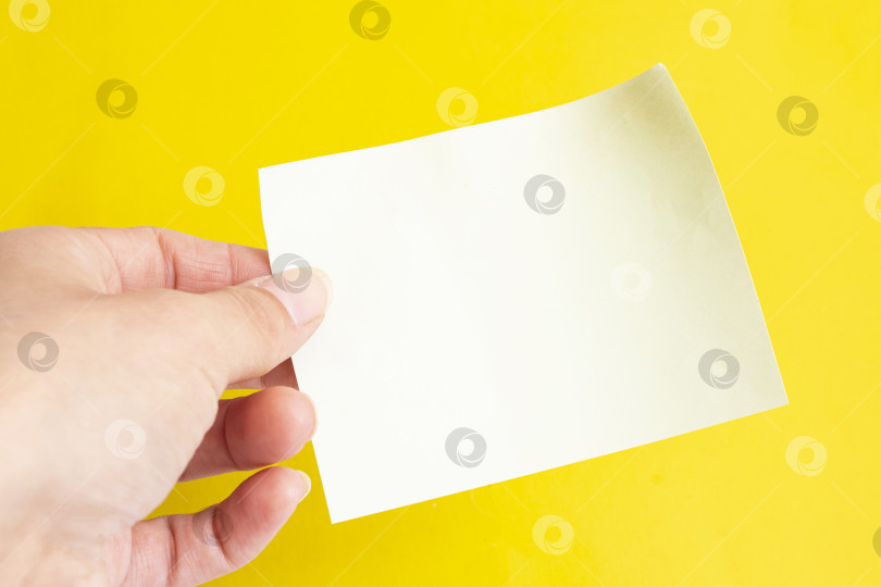 Скачать Чистый лист бумаги в руке на желтом фоне фотосток Ozero