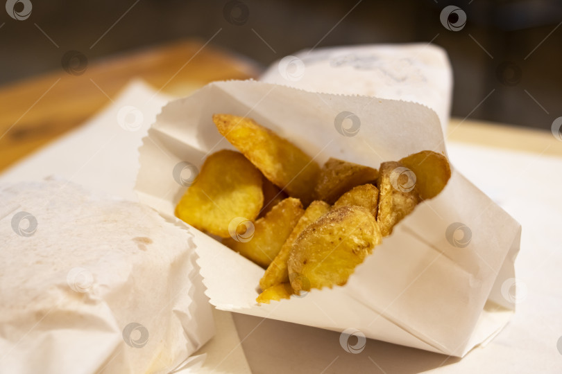 Скачать Жареные картофельные дольки, завернутые на столе фотосток Ozero