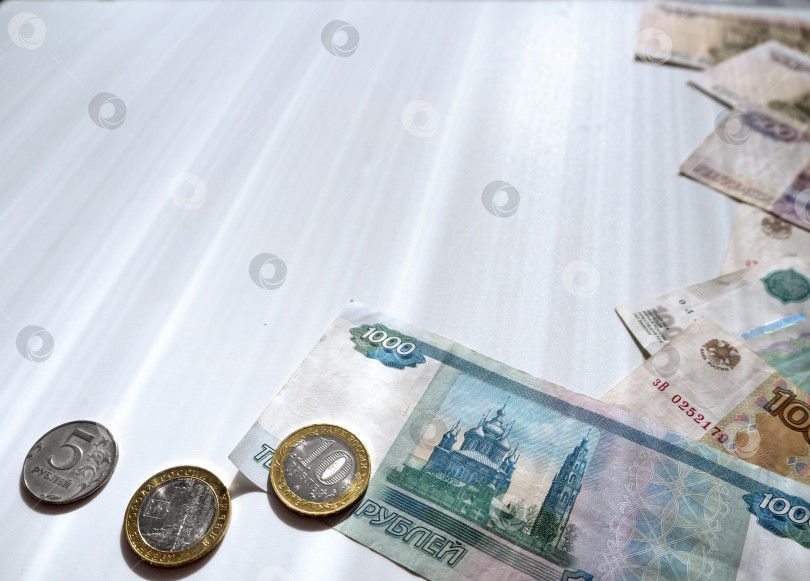 Скачать На белом фоне изображены российские купюры и монеты. Бумажные и металлические рубли расположены по периметру, справа и внизу. Фон с российскими деньгами и место для текста. фотосток Ozero
