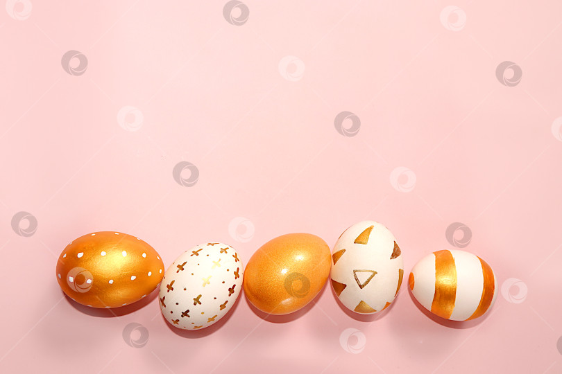 Скачать Украшенные золотые пасхальные яйца на розовом фоне. . Фон с Пасхой, баннер. Креативная роспись яиц в домашних условиях. Концепция праздника в минималистичном стиле, идея простых рисунков для раскрашивания фотосток Ozero