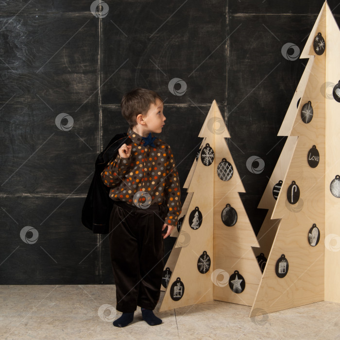 Скачать маленький мальчик рядом с декоративными рождественскими елками фотосток Ozero
