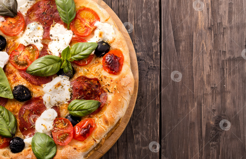 Скачать Деревенская пицца с салями, моцареллой, оливками и базиликом на деревянном фоне фотосток Ozero