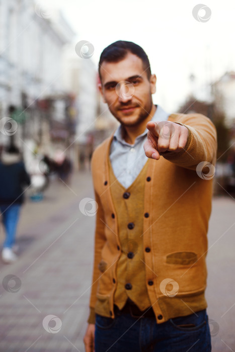 Скачать Молодой темноволосый мужчина на улице указывает на вас пальцем фотосток Ozero