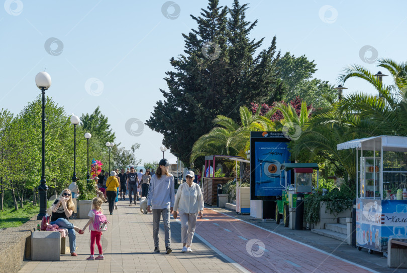 Скачать Люди прогуливаются по красивой набережной в Адлере. Город-курорт, входящий в состав города Сочи. Адлер, Сочи, Россия - 18 мая 2021 года фотосток Ozero