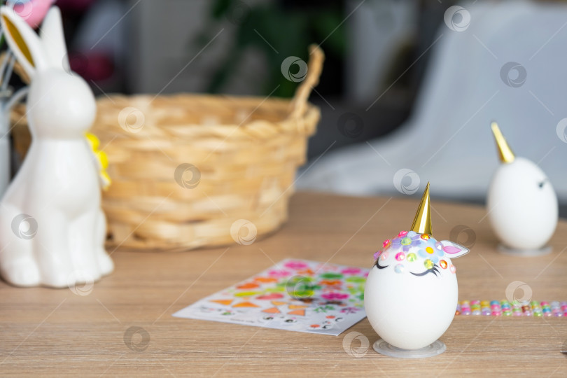 Скачать Пасхальная поделка - украшает яйцо в виде единорога стразами, рогом, цветами в интерьере дома фотосток Ozero