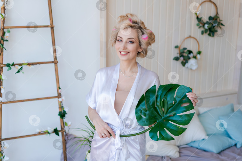 Скачать Женщина в белом халате держит в руках зеленое растение с листьями фотосток Ozero