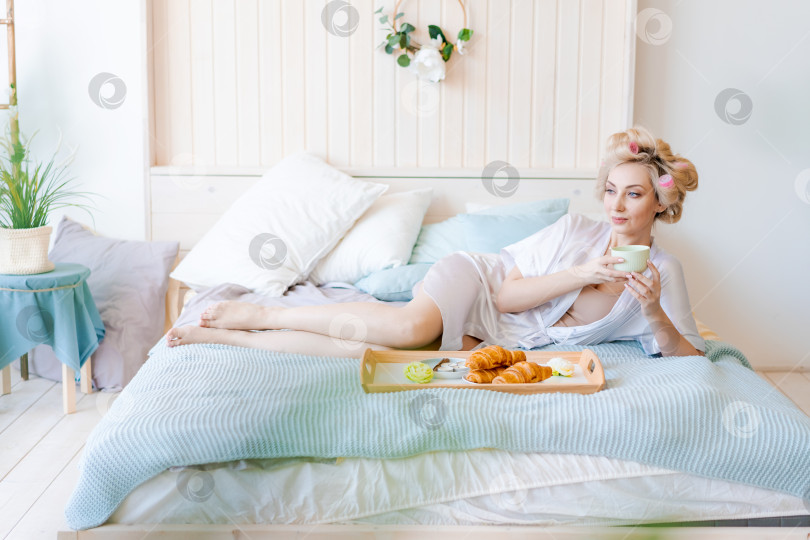 Скачать Женщина лежит на кровати, перед ней поднос с едой фотосток Ozero