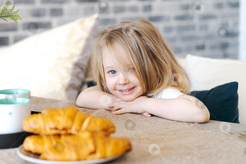 Скачать Молодая девушка сидит за столом с тарелкой круассанов фотосток Ozero