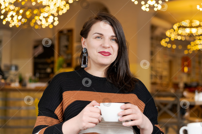 Скачать Женщина в полосатом свитере держит в руках белую кофейную чашку фотосток Ozero