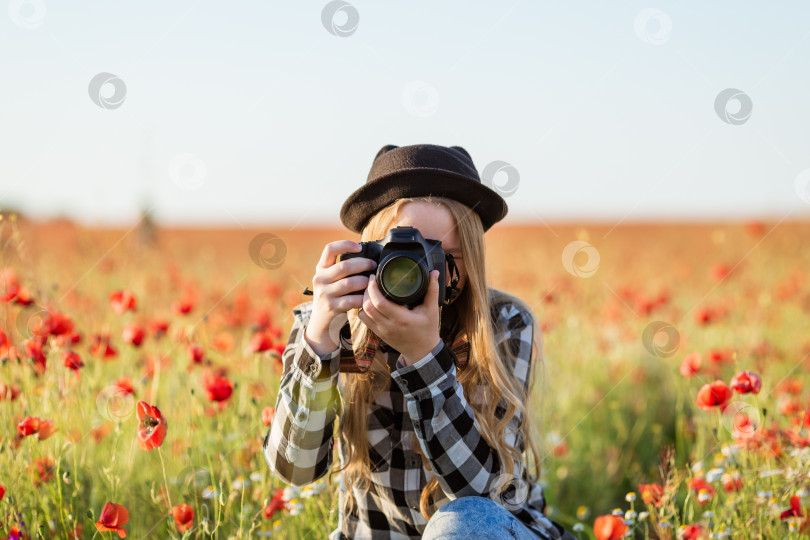 Скачать Женщина в шляпе и очках фотографирует поле с красными цветами фотосток Ozero