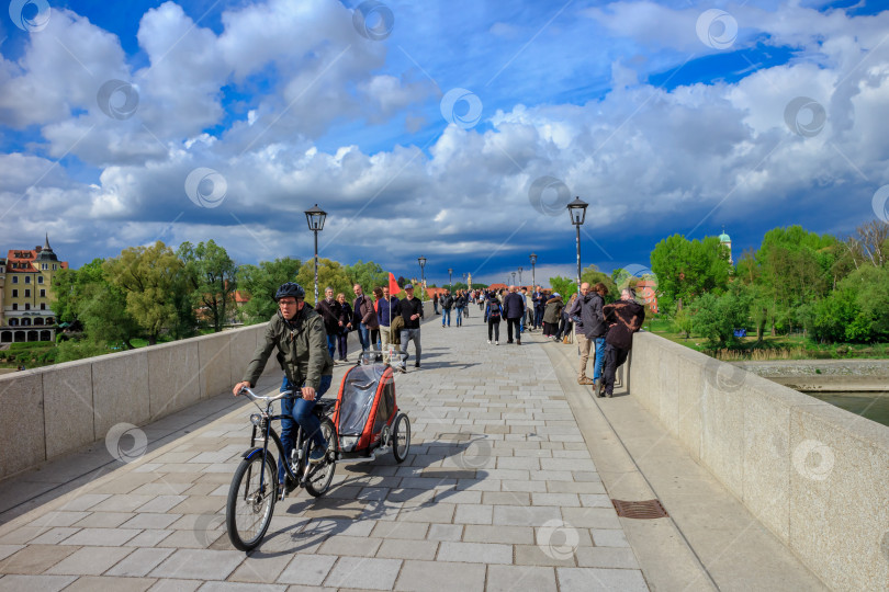 Скачать Туристы прогуливаются по историческому каменному мосту через реку Дунай в Регенсбурге Германия в солнечный день фотосток Ozero