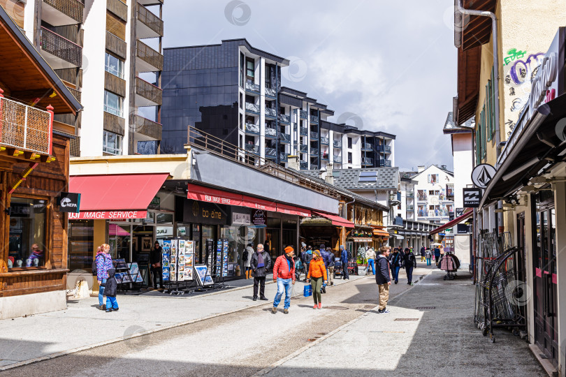 Скачать Центральная улица с кафе и магазинами в Шамони, по которой прогуливаются туристы фотосток Ozero