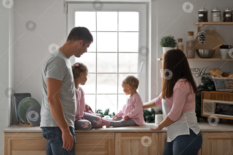 Скачать Молодая семья с двумя дочерьми готовится на кухне к новому году фотосток Ozero