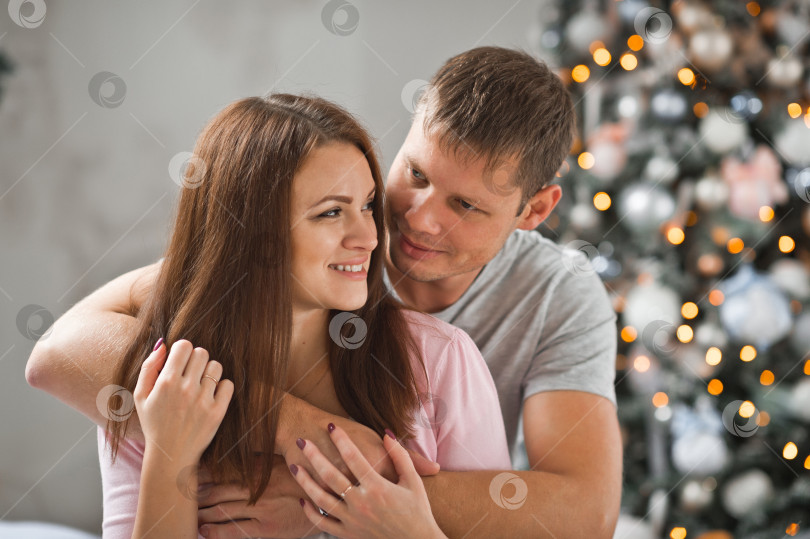 Скачать Муж и жена обнимаются на фоне рождественских украшений 1 фотосток Ozero