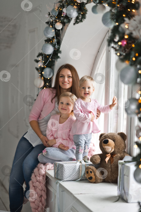 Скачать Мать с двумя маленькими дочерьми сидит на круглом подоконнике, украшенном фотосток Ozero