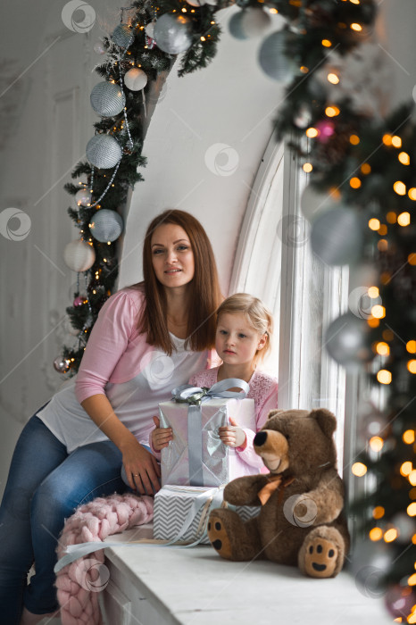 Скачать Мать с двумя маленькими дочерьми сидит на круглом подоконнике, украшенном фотосток Ozero