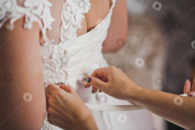 Скачать Руки матери застегивают свадебное платье на дочери в 1943 году. фотосток Ozero