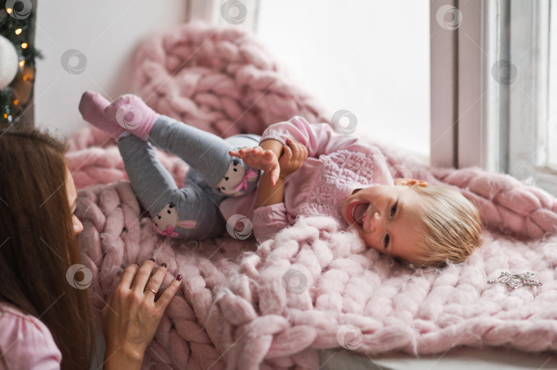 Скачать Малышка играет со своей мамой, лежа на розовом одеяле 2009 года. фотосток Ozero