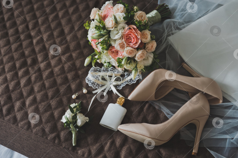 Скачать Красивый букет розовых роз и подвязка невесты лежат на столе. фотосток Ozero