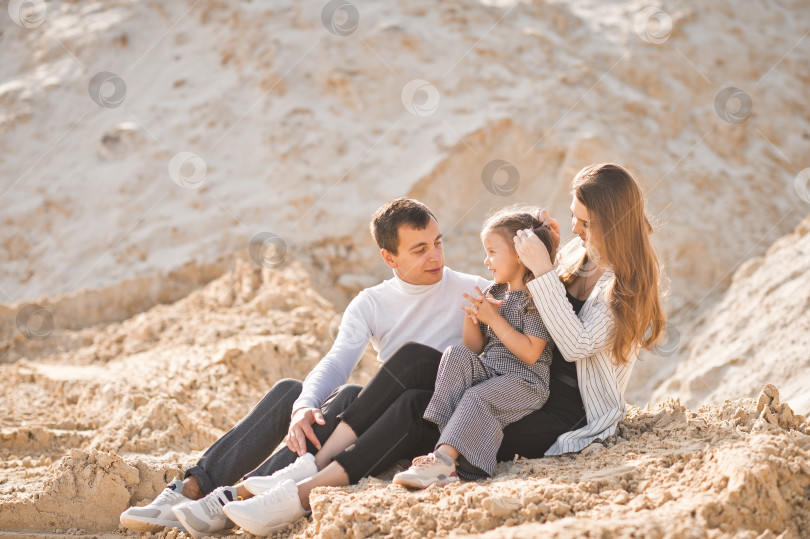 Скачать Семья из трех человек сидит среди гор песка 3351. фотосток Ozero