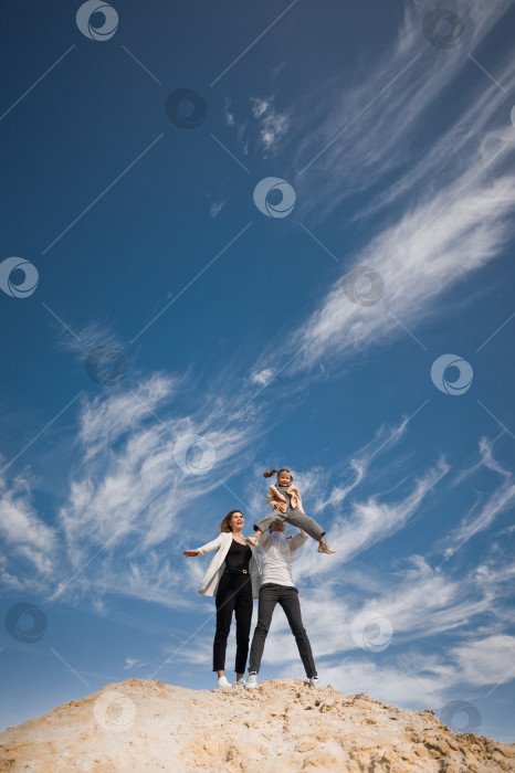 Скачать Семья позирует, стоя на горе песка на фоне неба 3311. фотосток Ozero