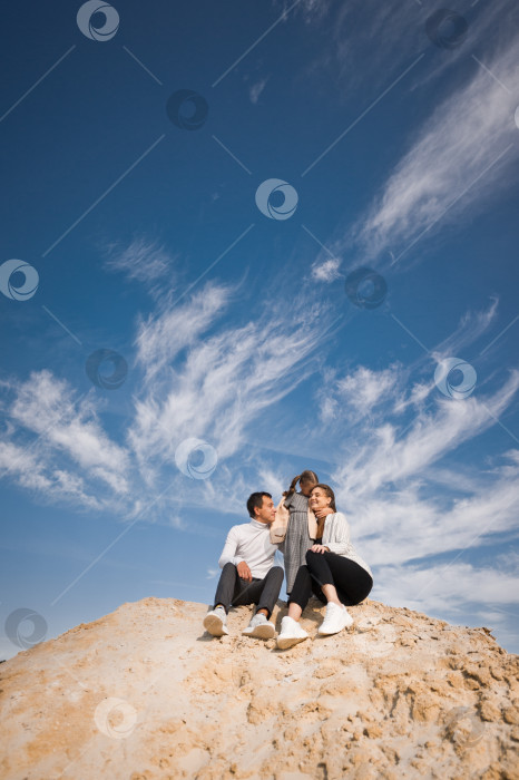 Скачать Семья позирует, стоя на горе песка на фоне неба 3313. фотосток Ozero