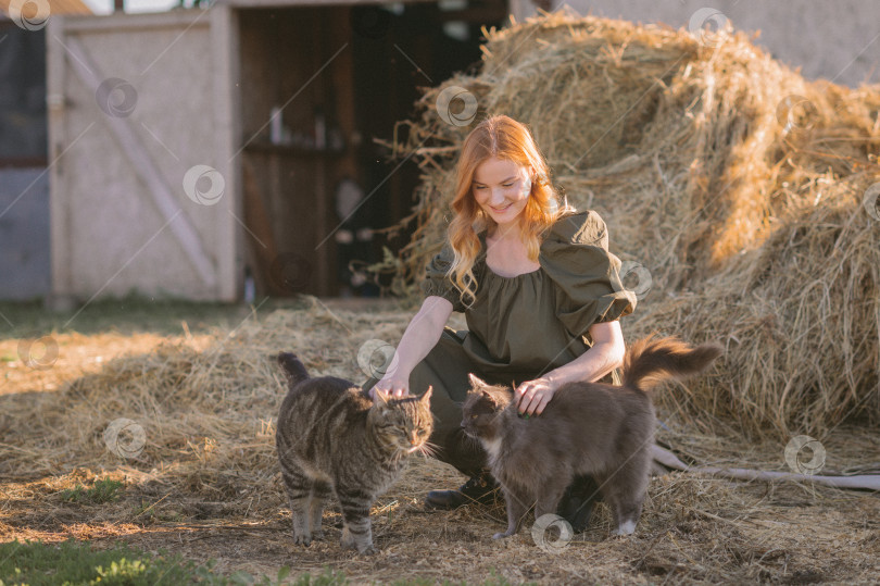 Скачать Девочка и две кошки возле стога сена 3267. фотосток Ozero