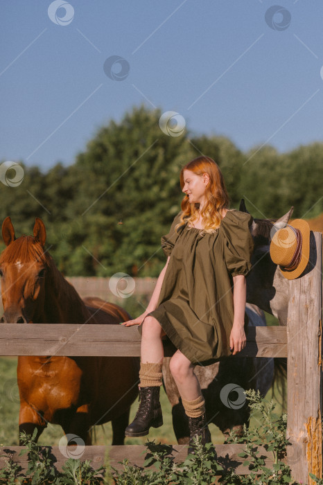 Скачать Девушка с рыжими волосами гладит и кормит травой лошадей 3250. фотосток Ozero