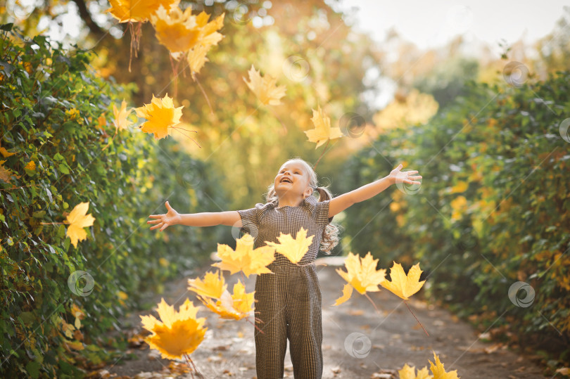 Скачать Маленькая дочка играет с осенними листьями в парке 3382. фотосток Ozero