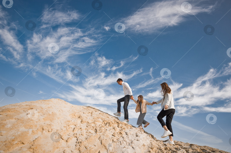 Скачать Молодая семья с дочерью среди песка и голубого неба 3309. фотосток Ozero