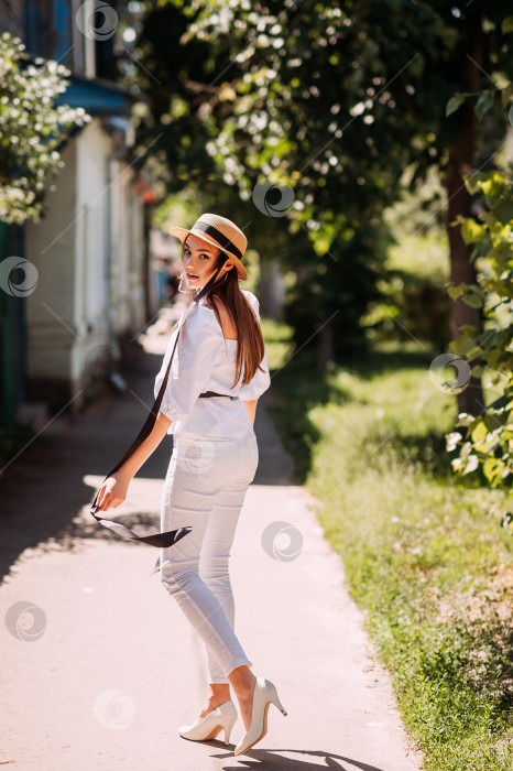 Скачать Молодая девушка в шляпке на фоне цветущих улиц города фотосток Ozero