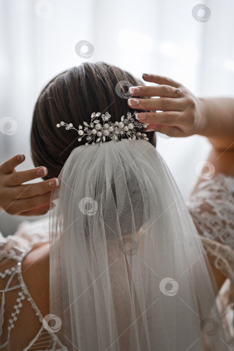 Скачать Невеста поправляет свадебную фату и жемчужные украшения в волосах 2530. фотосток Ozero