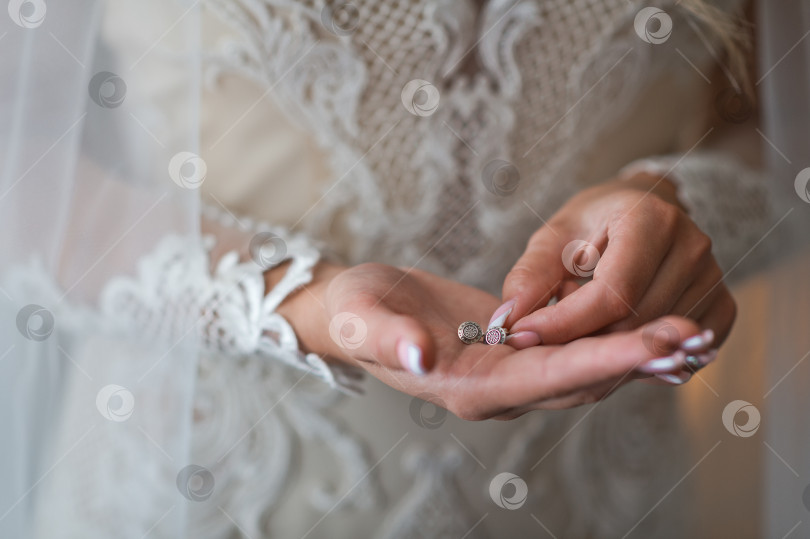 Скачать Невеста держит серьги в руках, прежде чем надеть их на 2377. фотосток Ozero