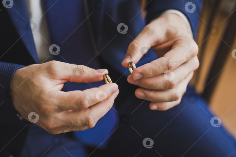 Скачать Жених держит золотые обручальные кольца на своих пальцах 2560. фотосток Ozero