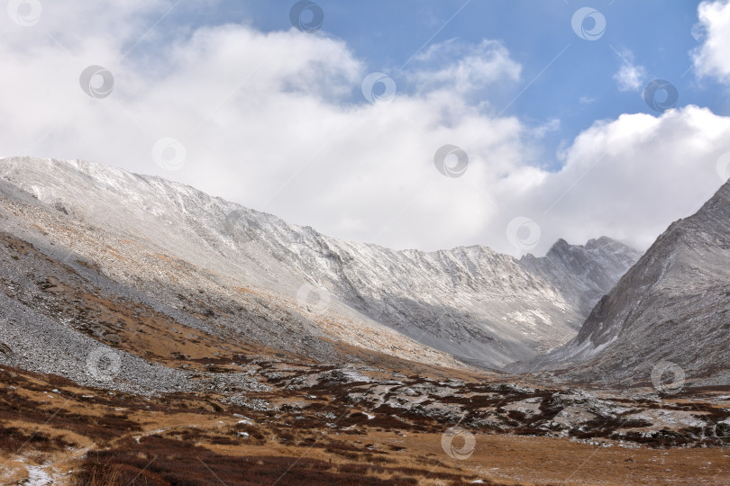 Скачать Крутые склоны высокого горного хребта спускаются в живописную долину, присыпанную первым снегом, под пасмурным осенним небом. фотосток Ozero