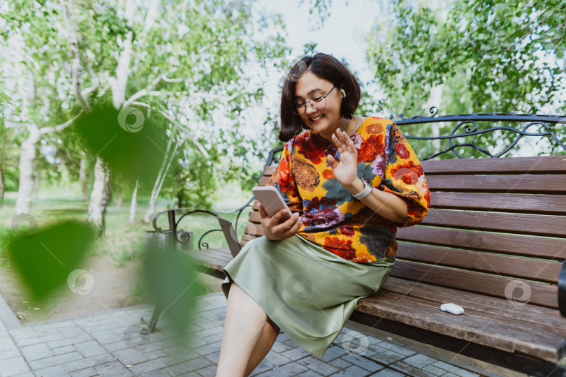 Скачать Веселая взрослая дама в очках вела телефонный разговор, сидя в парке фотосток Ozero
