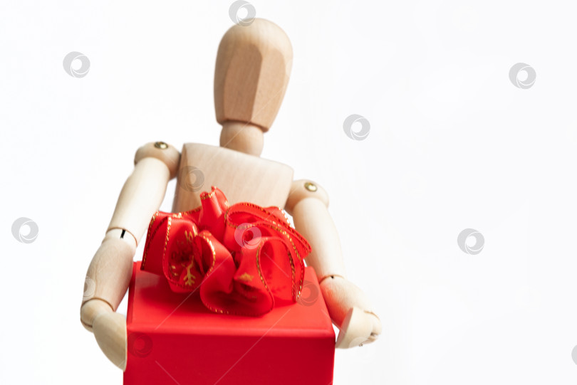 Скачать Деревянный манекен держит подарочную коробку с красным бантом фотосток Ozero