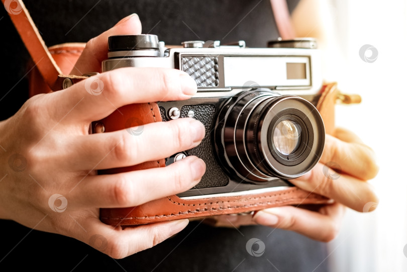 Скачать Женщина держит в руке старую винтажную пленочную зеркальную фотокамеру в кожаном чехле фотосток Ozero