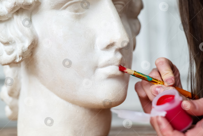 Скачать Художник наносит красный оттенок на губы модели Apollo head фотосток Ozero