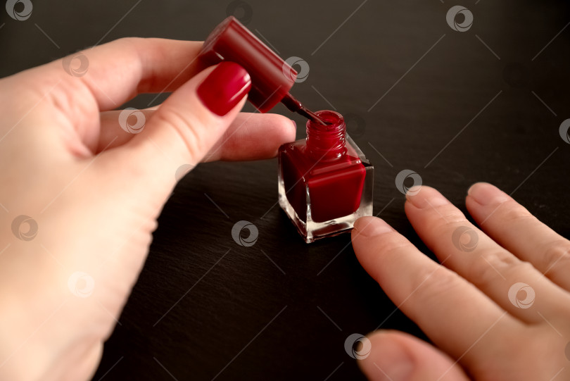 Скачать Крупным планом руки женщины, наносящей красный лак на ногти фотосток Ozero