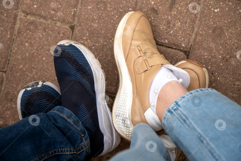 Скачать Посмотрите вниз на пару человеческих ног, одетых в повседневные ботинки или туфельки фотосток Ozero