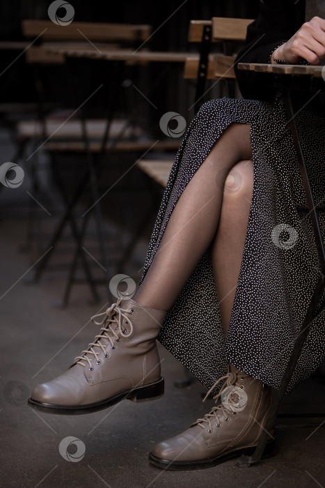 Скачать крупным планом скрещенные ноги женщины в кожаных сапогах, сидящей в уличном кафе фотосток Ozero