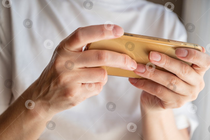 Скачать Женщина, держащая в руках мобильный телефон, отправляет текстовые сообщения или играет в игры фотосток Ozero