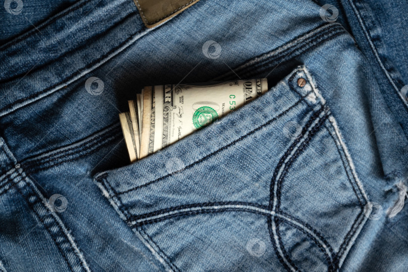 Скачать из заднего кармана старых джинсов выглядывает несколько долларовых банкнот фотосток Ozero